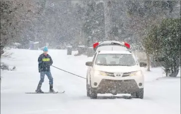  ?? Mic Smith Associated Press ?? SID RISMANI skis behind a vehicle during heavy snow in Isle of Palms, S.C. Cold temperatur­es swept as far south as Florida. In other parts of the country, it was so cold that a water tower froze solid — as did a shark.