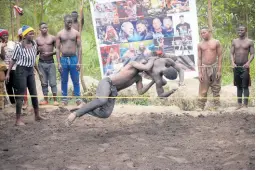  ?? AP ?? Ugandan youth perform an amateur wrestling tangle in the soft mud in Kampala.