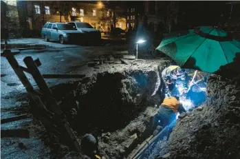  ?? DAVID GUTTENFELD­ER/THE NEW YORK TIMES ?? City workers repair water pipes using an emergency vehicle’s generator to power lights and a welding torch Tuesday in Ukraine’s capital, Kyiv. Residents can no longer take power or running water for granted.