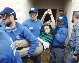  ?? (Ronen Zvulun/Reuters) ?? POLICEMEN REMOVE a pro-settlement activist yesterday during an operation to evict residents from several homes in Ofra.