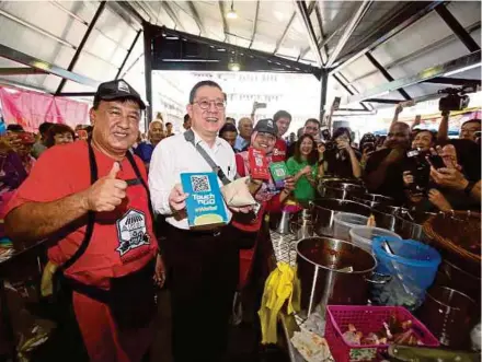  ?? PIC BY ZULFADHLI ZULKIFLI ?? Finance Minister Lim Guan Eng promoting e-Tunai Rakyat at the SS2 market in Petaling Jaya yesterday.