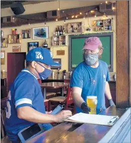  ?? BRIAN CASSELLA/CHICAGO TRIBUNE ?? Bartender Wally List serves the first beer to customer Christian Trezvant on June 17 as The Green Lady bar in Lakeview reopened.