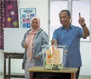  ?? ?? Duty done: (Top) Ismail Sabri with his wife datin Seri muhaini Zainal abidin dropping their ballot papers into the boxes at SMK Kerayong in bera, Pahang. (above) muhyiddin and his wife, Puan Sri noorainee abdul rahman, casting their votes at SMK Sri muar in muar, Johor.