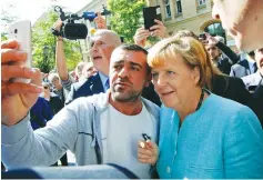  ?? (Fabrizio Bensch/Reuters) ?? GERMAN CHANCELLOR Angela Merkel poses for a selfie with a migrant in September 2015 outside a refugee camp near the Federal Office for Migration and Refugees in Berlin’s Spandau district.