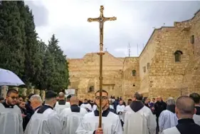  ?? AP PHOTO/LEO CORREA ?? Catholic clergy walk in procession next to the Church of the Nativity, traditiona­lly believed to be the birthplace of Jesus, on Christmas Eve in the West Bank city of Bethlehem.