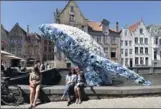  ?? JOHN THYS / AFP ?? Tourists pose for a selfie with a 12-meter installati­on depicting a whale, made up of five tons of plastic waste, displayed in Brugges, Belgium, on Saturday.