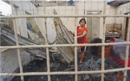  ?? SUNSTAR FOTO / ALLAN CUIZON ?? THE DAY AFTER. One of the families affected by the fire in Barangay Basak Pardo, Cebu City checks what’s left of their house and collects debris that can be sold to the local junk shop.