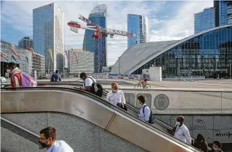  ?? Michel Euler / Associated Press ?? People ride an escalator as they arrive Friday at La Defense business district in Paris while wearing face masks as a precaution against the coronaviru­s.