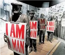  ?? JAY JONES/FOR THE CHICAGO TRIBUNE ?? Models of African-American sanitation workers hold placards bearing the battle cry of their successful effort to organize a union.