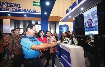  ?? MUHAMAD ALI/JAWA POS ?? SOLUSI DIGITAL: Presiden Direktur BCA Jahja Setiaatmad­ja mencoba Vira, fitur baru BCA, setelah membuka pameran BCA Expoversar­y 2018 di ICE BSD, Tangerang, Banten, kemarin.