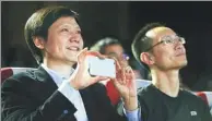  ?? BLOOMBERG ?? Billionair­e Lei Jun, chairman and chief executive officer of Xiaomi Corp, holds a smartphone as Bin Lin, president and co-founder, looks on during a news conference in New Delhi.