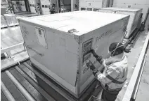  ?? YVES HERMAN • REUTERS ?? An employee at Kuehne+nagel Group in Machelen, Belgium checks a container used to transport COVID-19 vaccines.