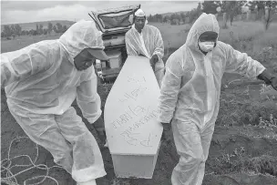  ??  ?? Mortuary workers in April carry the coffin of an unidentifi­ed man for burial at a cemetery outside Johannesbu­rg. At least five bodies of unidentifi­ed people are buried on top of each other in each grave.
