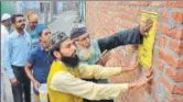  ?? SACHIN SAINI/HT ?? Ejaz Ahmed Barkati (in yellow) and imams of the area paste pamphlets in Faridapur, announcing the ban on loud music in marriage functions.