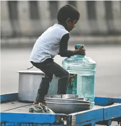  ?? IDREES MOHAMMED / AFP VIA GETTY IMAGES ?? A boy struggles with a water container amid the ongoing
water crisis in Bengaluru, India, on Sunday.