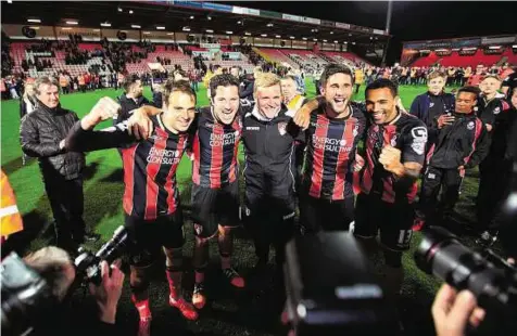  ?? Rex Features ?? On cloud nine Bournemout­h players and manager Eddie Howe (centre) pose for photograph­ers after they got the better of Bolton Wanderers at the Goldsands Stadium on Monday to effectivel­y seal promotion to the Premier League for the first time.