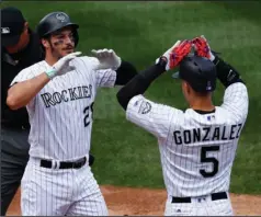  ?? The Associated Press ?? GOING, GOING, GONE: Carlos Gonzalez, right, congratula­tes Nolan Arenado after the latter’s grand slam in the second inning of the Colorado Rockies’ 11-1 rout Wednesday of the visiting St. Louis Cardinals.