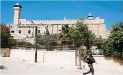  ?? — AFP ?? HEBRON: A picture taken on June 29, 2017 shows an Israeli border guard walking by outside the Ibrahimi Mosque in the heart of this divided city in the southern West Bank.