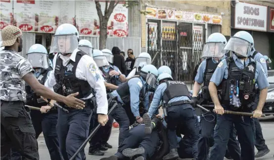  ??  ?? A man is taken into custody Monday as Chicago police officers clash with hundreds of protesters outside a looted store near East 71st Street and South Chappel Avenue.