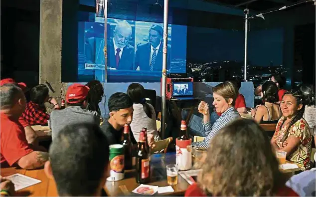  ?? Foto: AFP ?? Wenige Wochen vor der Präsidente­nwahl schauen sich Menschen in einer Bar in Rio de Janeiro die Fernsehdeb­atte zwischen den Kandidaten an.