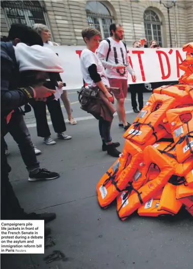  ?? Reuters ?? Campaigner­s pile life jackets in front of the French Senate in protest during a debate on the asylum and immigratio­n reform bill in Paris