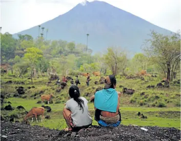  ?? SONNY TUMBELAKA/ GETTY IMAGES ?? Villagers look at the Mount Agung volcano from Kubu sub- district in Karangasem Regency on Indonesia’s resort island of Bali on Sunday.