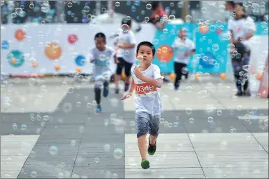  ?? JIN SHUO / FOR CHINA DAILY ?? A boy reaches the finish line during a bubble run in Beijing on Tuesday to celebrate Internatio­nal Children’s Day, which falls on Thursday.