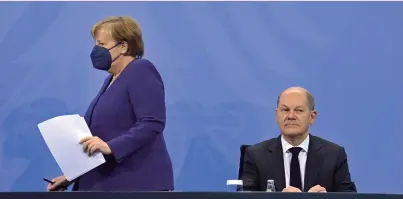  ?? ?? La canciller en funciones, Angela Merkel, llega a la rueda de prensa para anunciar las nuevas
restriccio­nes y se sienta junto a su sucesor, Olaf Scholz, este jueves en Berlín.