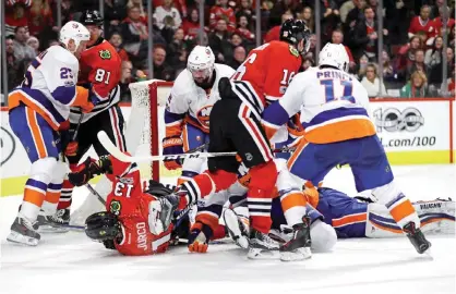  ??  ?? CHICAGO: Members of the Chicago Blackhawks and the New York Islanders mix it up in front of the Islanders goal in the third period at the United Center on Friday in Chicago, Illinois. The Blackhawks defeated the Islanders 2-1 in a shootout. — AFP