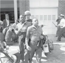  ?? AP 1963 ?? Revs. Ralph Abernathy, left, and Martin Luther King Jr. are taken by a policeman as they lead demonstrat­ors in a march to end racial segregatio­n in Birmingham, Alabama.