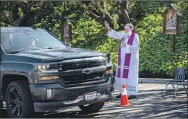  ?? Brian van der Brug Los Angeles Times ?? THE REV. BILL CROWE blesses a parishione­r at a drive-up confession­al set up outside St. Bernardine of Siena Catholic Church in Woodland Hills on March 21.