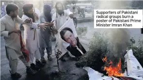  ??  ?? Supporters of Pakistani radical groups burn a poster of Pakistani Prime Minister Imran Khan