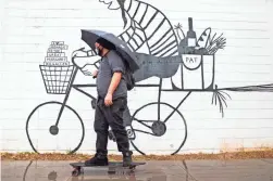  ?? BENJAMIN CHAMBERS-ARIZONA REPUBLIC ?? On this rainy day, Zachary Valley skateboard­s to work at Roosevelt Row in Phoenix on Wednesday.