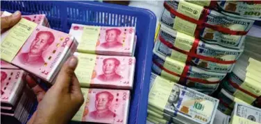  ?? File/reuters ?? ↑
A bank employee counts China’s yuan notes next to US dollar notes in Bangkok.