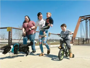  ?? ISABELLA VOLMERT/AP ?? Emerson Howard, left, and her dog, Dixie, enjoy a walk March 13 along with Destiny Porter and her children at the Kitselman bridge connecting the Cardinal Greenway and White River Greenway trails in Muncie, Indiana.