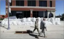  ?? CHARLIE NEIBERGALL — THE ASSOCIATED PRESS ?? Iowa National Guard members walk past a local business covered in sandbags, Monday in Cedar Rapids, Iowa. Residents are waiting anxiously as a quickly rising Cedar River threatens to inundate their city with devastatin­g floodwater­s for the second time...