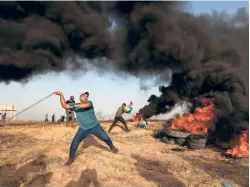  ?? ?? A PALESTINIA­N PROTESTER uses a slingshot to hurl stones across the border at the Gaza Strip on October 25.