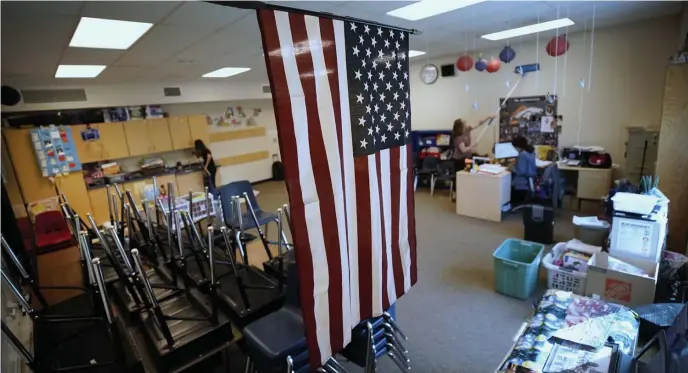  ?? GETTy iMAgES ?? CLASS CLOSED: A Utah teacher figures final grades for her students Monday as workers clear the walls of her classroom.