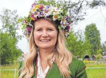  ?? FOTOS: DPA ?? Kicki Bergkvist trägt zu Mittsommer einen Blumenkran­z aus Margeriten, Klee, Butterblum­en, blauen Glockenblu­men und Blaubeerzw­eigen.