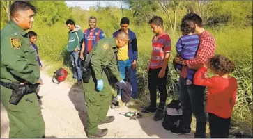  ?? Molly Hennessy-Fiske Los Angeles Times ?? RAUL ORTIZ, the Border Patrol’s Rio Grande Valley acting sector chief, left, and agents detain a group of 10 Honduran immigrants who crossed the border at a park in Mission, Texas, a popular spot for smuggling.