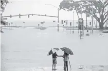  ?? HOLLYN JOHNSON, AP ?? People stand near floodwater­s from Hurricane Lane in Hilo on Hawaii’s Big Island on Thursday.