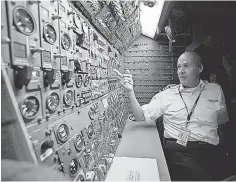  ??  ?? Flight engineer Lance Pruitt surveys his station — and its button- filled console — on the Boeing 747- 200 flight deck.