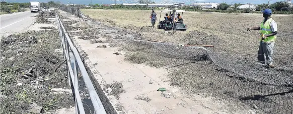  ?? NORMAN GRINDLEY/CHIEF PHOTO EDITOR ?? Officials look at a section of Tinson Pen Aerodrome fence which collapsed under the weight of the floodwater­s on Marcus Garvey Drive last Tuesday.