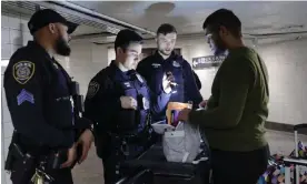  ?? Photograph: Anadolu/Getty Images ?? Officers check bags on the subway in New York on Thursday.