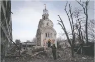  ?? EVGENIY MALOLETKA / THE ASSOCIATED PRESS ?? A Ukrainian serviceman takes a photograph on Thursday
of a damaged church in Mariupol, Ukraine.