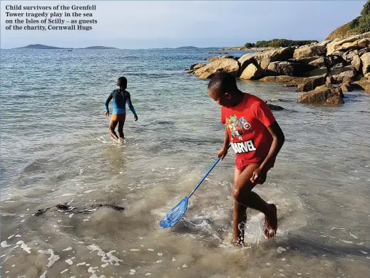  ??  ?? Child survivors of the Grenfell Tower tragedy play in the sea on the Isles of Scilly – as guests of the charity, Cornwall Hugs