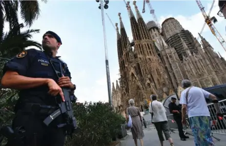  ?? PASCAL GUYOT/AFP/GETTY IMAGES ?? A police officer stands by the Sagrada Familia basilica in Barcelona on Sunday before a mass to commemorat­e victims of two terror attacks in Spain.