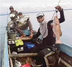  ??  ?? Omar Ali (belakang) bersama rakan ketika memancing di Felda Sahabat 16, Lahat Datu, Sabah.