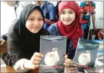  ?? ANDINA/JAWA POS ?? PRODUKTIF: Dua siswa SMA Kanjeng Sepuh, Sidayu, memperliha­tkan buku antologi puisi Kematian Bulan.