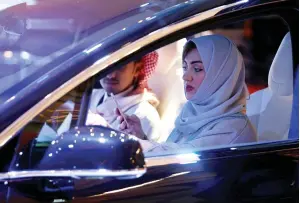  ??  ?? A Saudi woman uses her smartphone as she checks a car at a showroom in Riyadh. (Reuters)